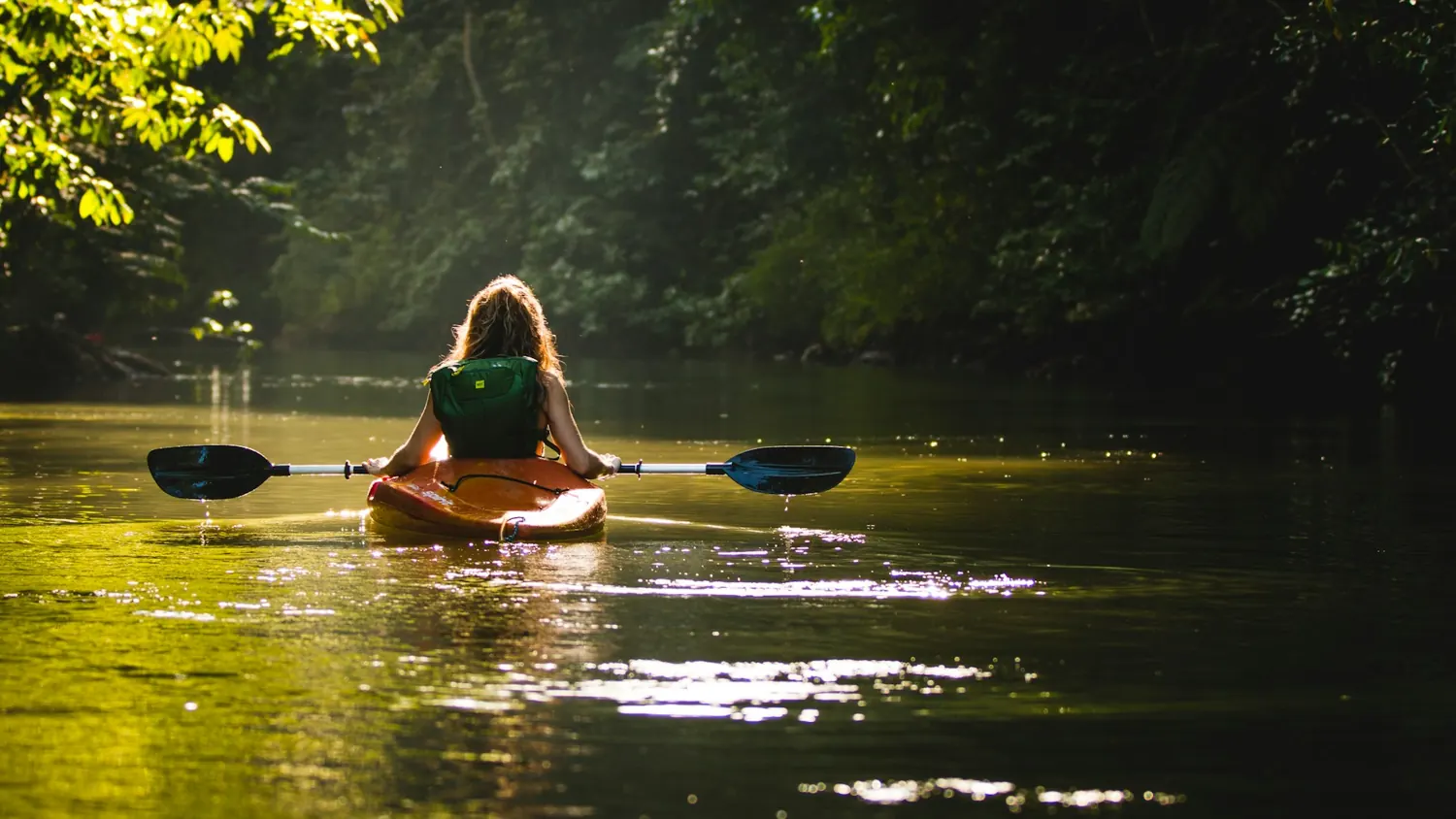 A kayaker crossing calm water in the evening light